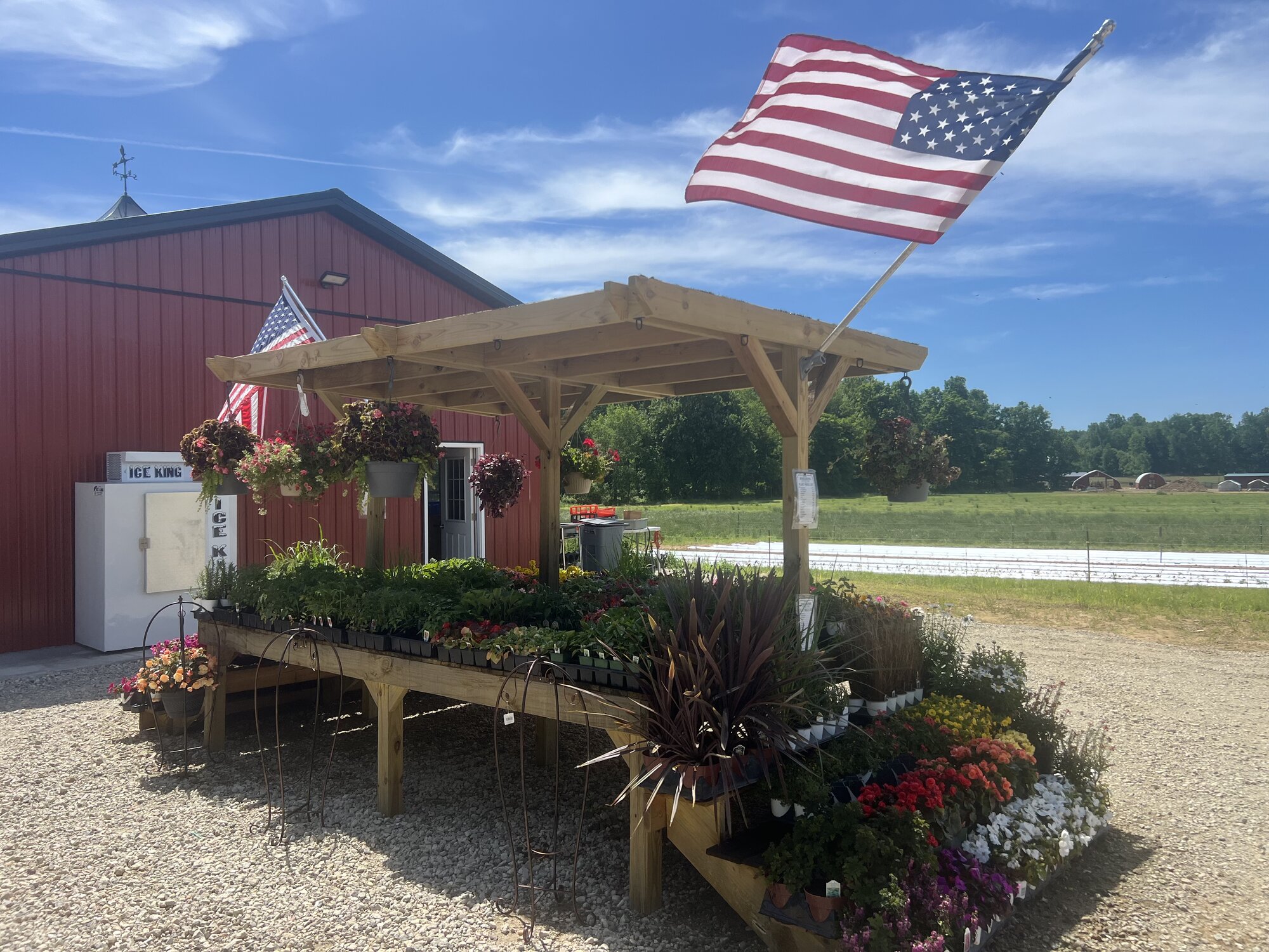 Plant stand beside the red barn with American flag