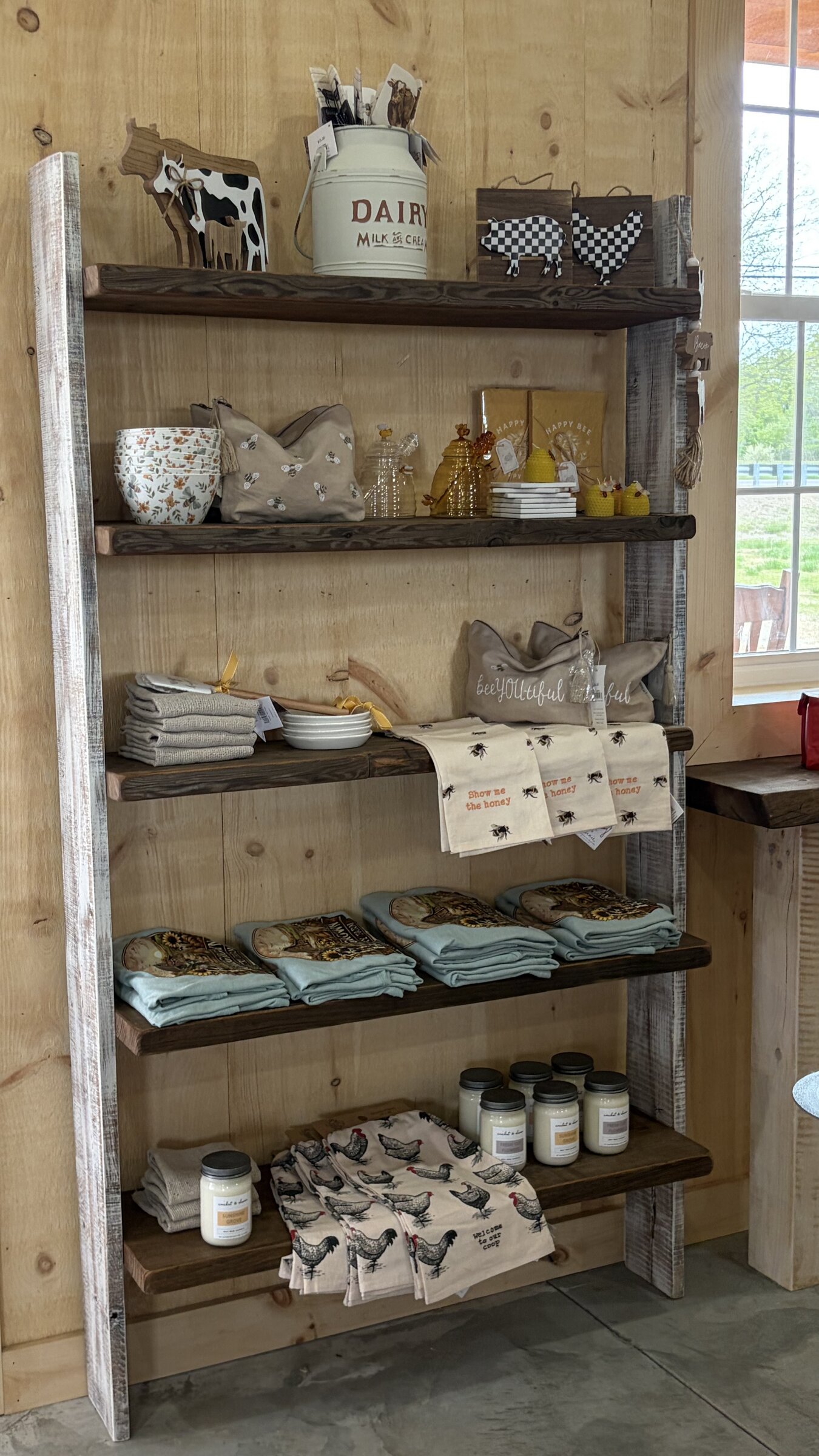 Tall ladder shelf with dairy decor, bee goods, towels, and candles