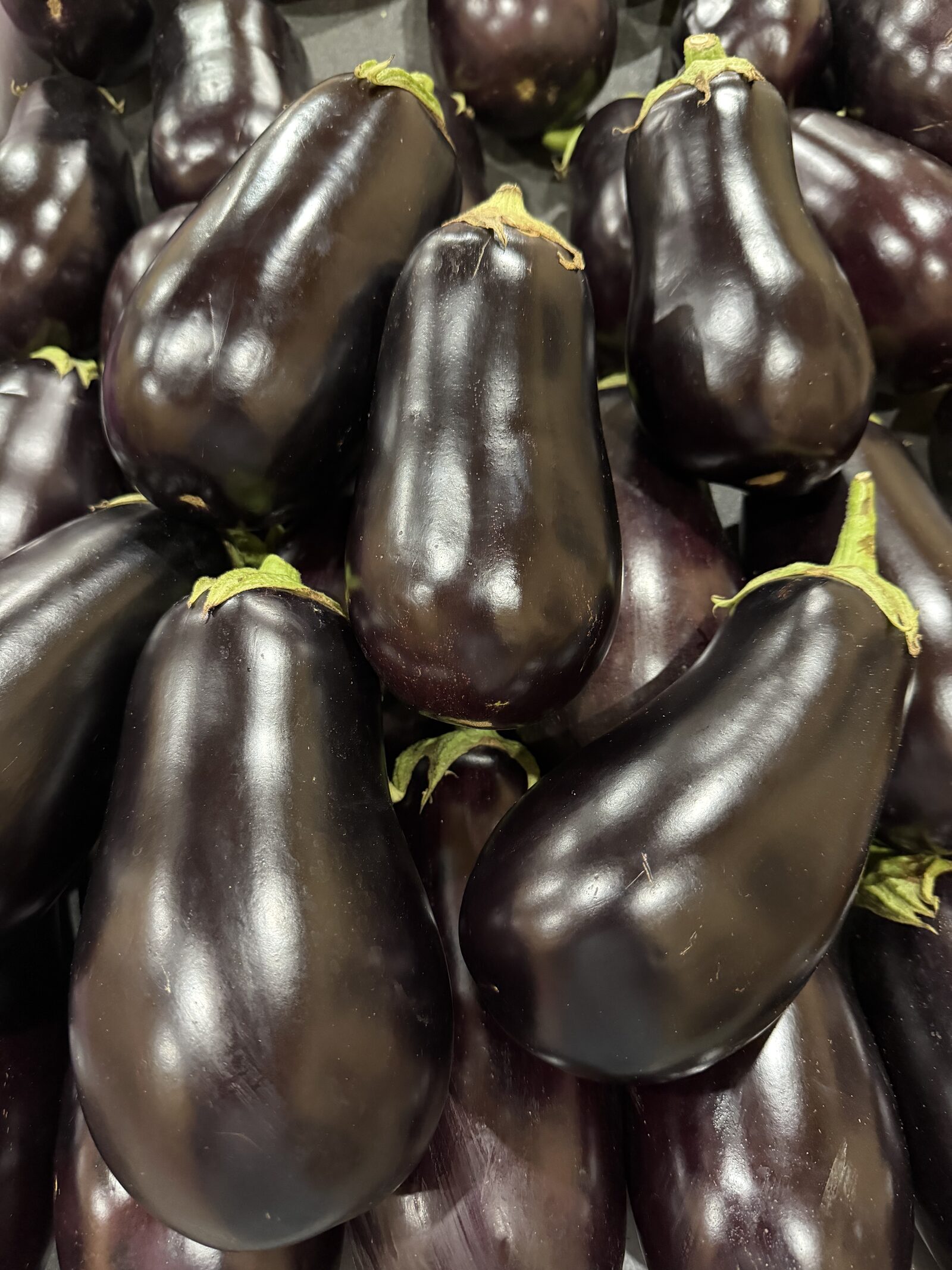 Glossy purple eggplants stacked in a display crate